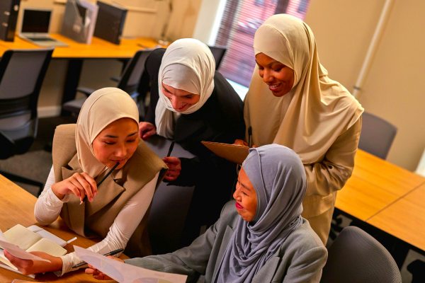 A group of four smiling women studying together