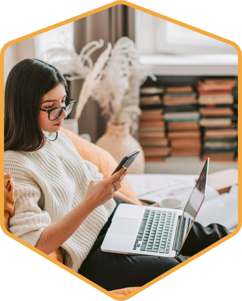 Seated woman looking at phone with laptop on lap